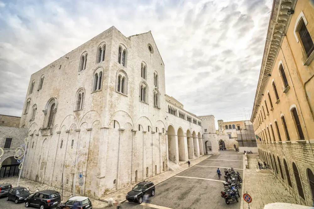 Una vista della basilica di san nicola nel centro storico di bari con auto parcheggiate.