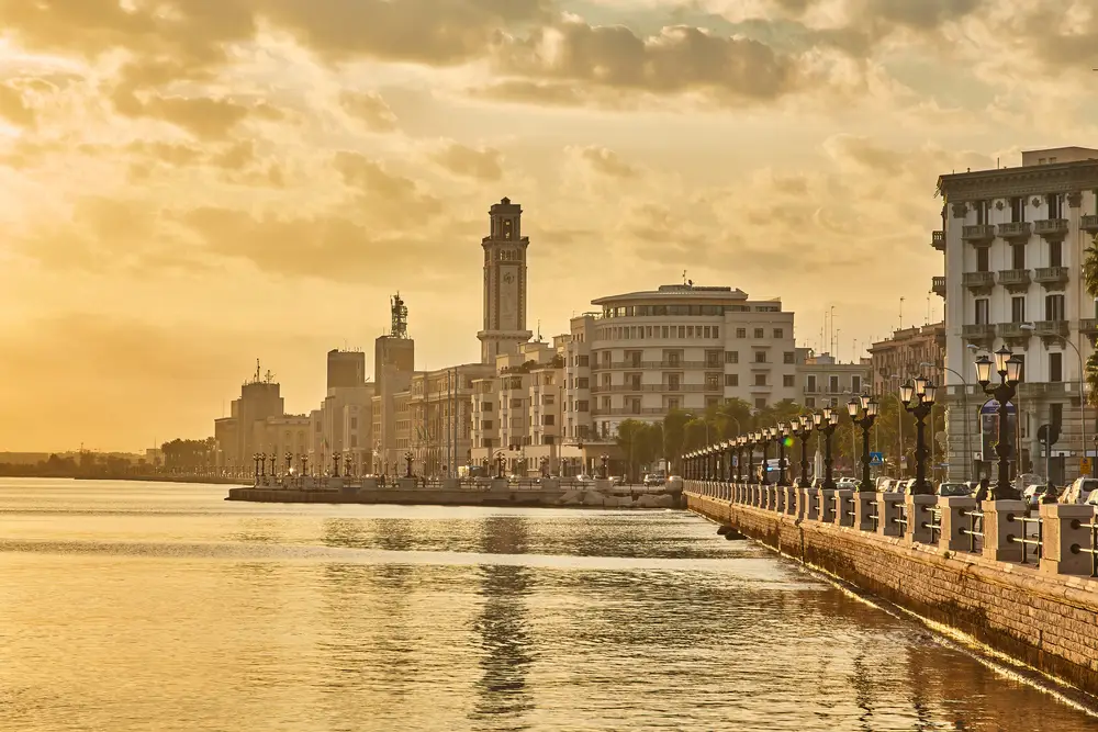 Il Lungomare di Bari con l'albergo delle nazioni e la pinacoteca provinciale sullo sfondo all'imbrunire.